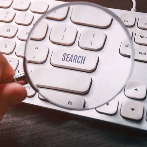 Search button key on computer keyboard seen through magnifying glass