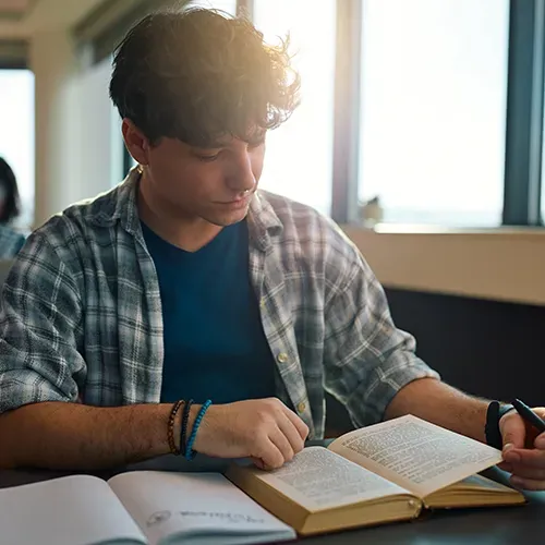 college student in a library looking down at a book
